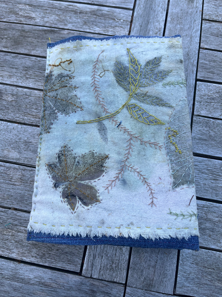 stitched eco print book cover placed on a wooden garden table
